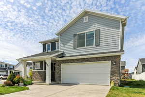 Craftsman house with stone siding, an attached garage, and concrete driveway