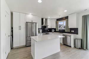 Kitchen featuring stainless steel appliances, white cabinetry, light wood-style floors, light stone countertops, and recessed lighting