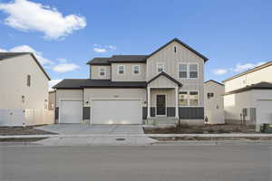 View of front of house with board and batten siding, driveway, and a gate
