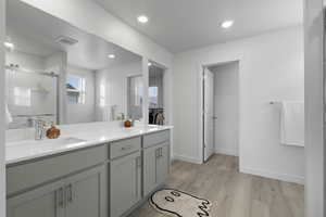 Bathroom with double vanity, a stall shower, light wood-style flooring, recessed lighting, and a textured ceiling