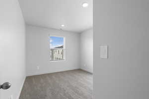 Empty room with light carpet and recessed lighting