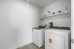 Washroom with light wood-style floors and washer and dryer