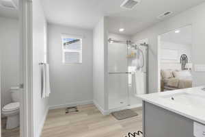 Full bathroom with vanity, a stall shower, and light wood-style flooring