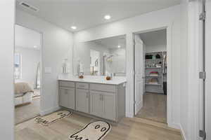 Ensuite bathroom with a stall shower, double vanity, a spacious closet, light wood finished floors, and recessed lighting