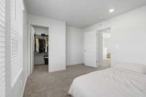 Bedroom with a spacious closet and light carpet