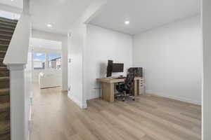 Office with light wood finished floors and recessed lighting