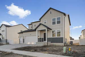 View of front of property with board and batten siding, concrete driveway, and an attached garage
