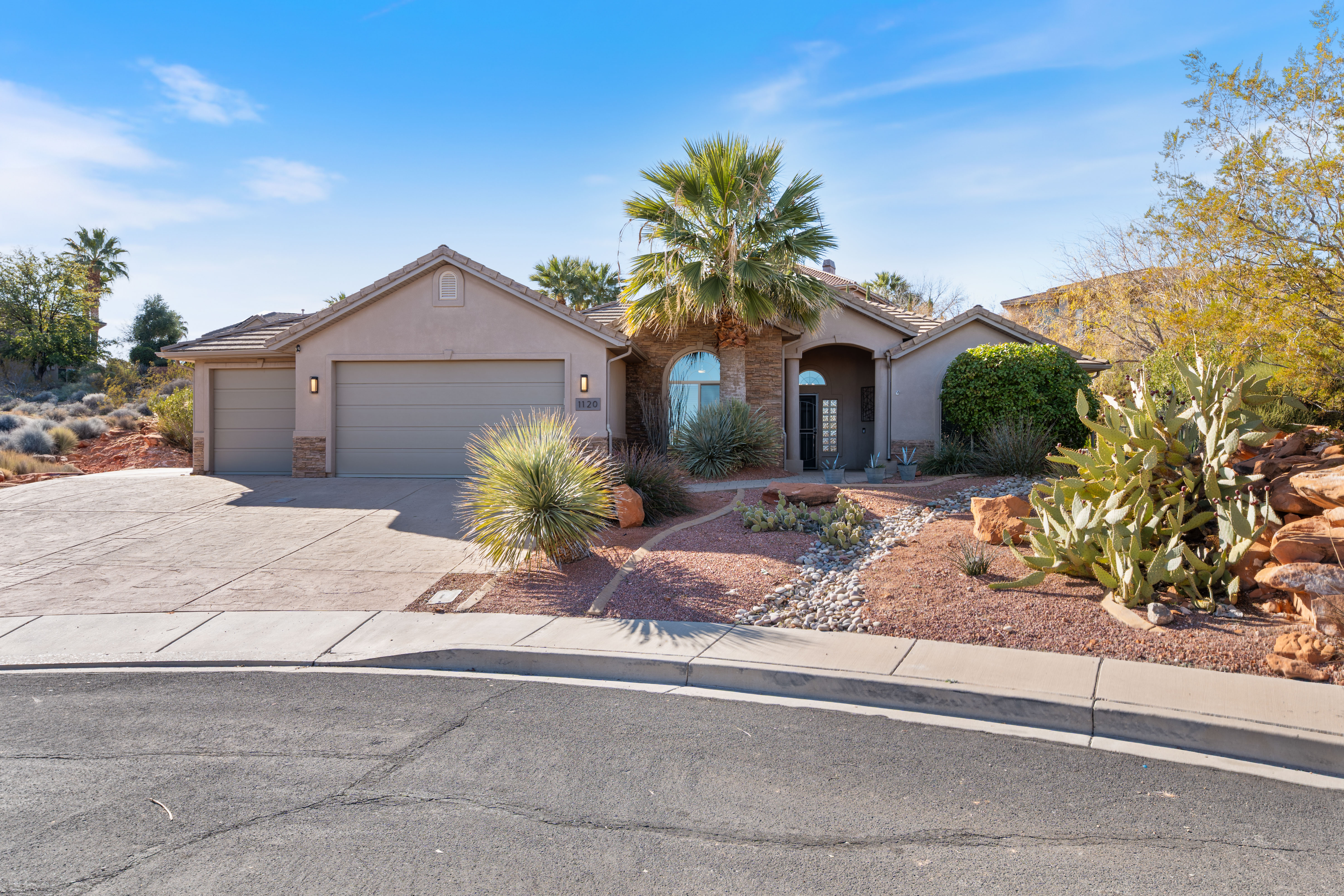 View of front of property featuring an attached garage, driveway, stucco siding, and a tiled roof