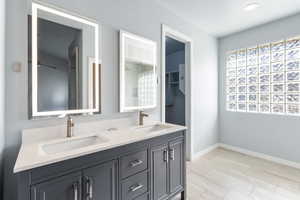 Full bath with double vanity and wood finish floors
