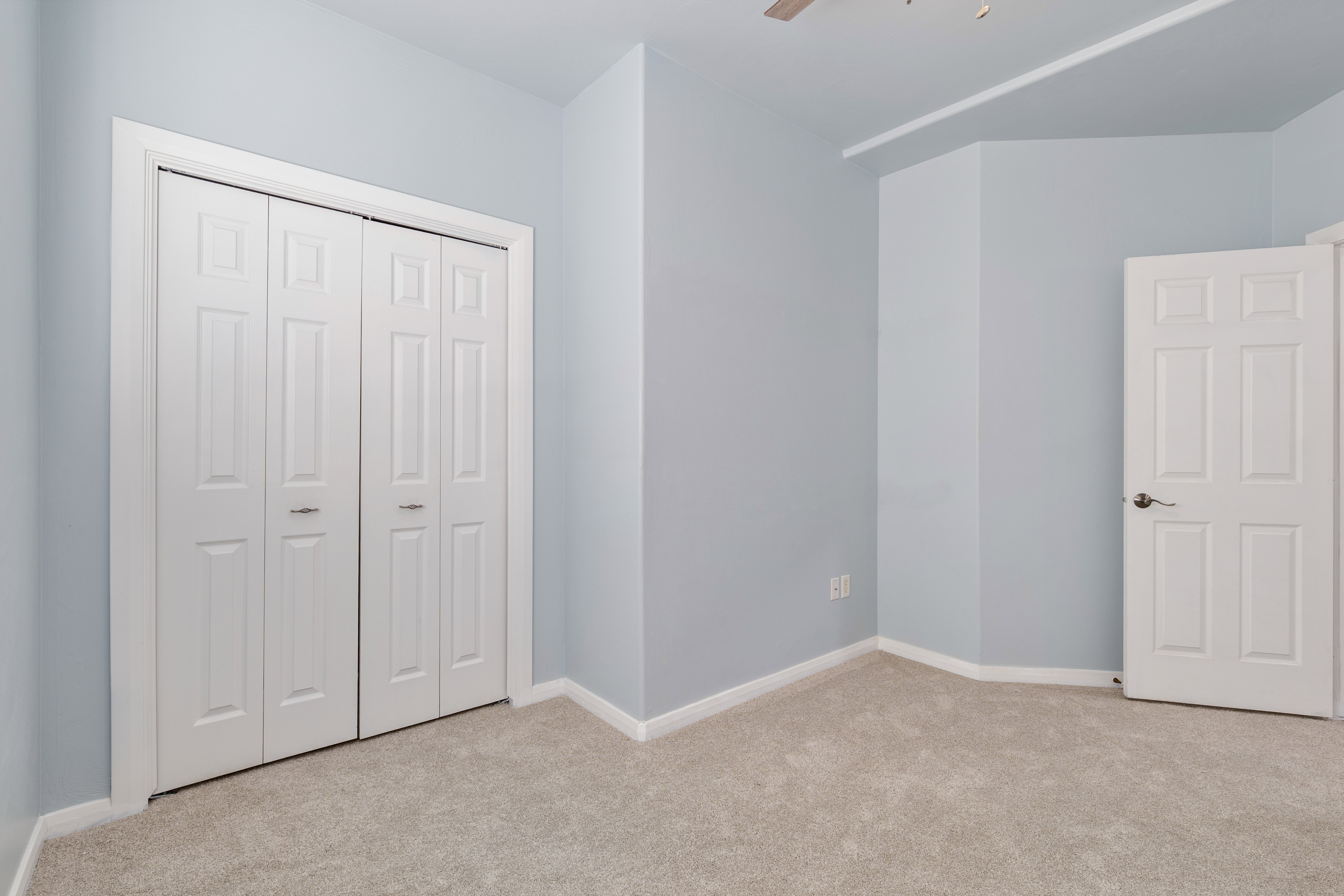 Unfurnished bedroom with light colored carpet, a closet, and a ceiling fan