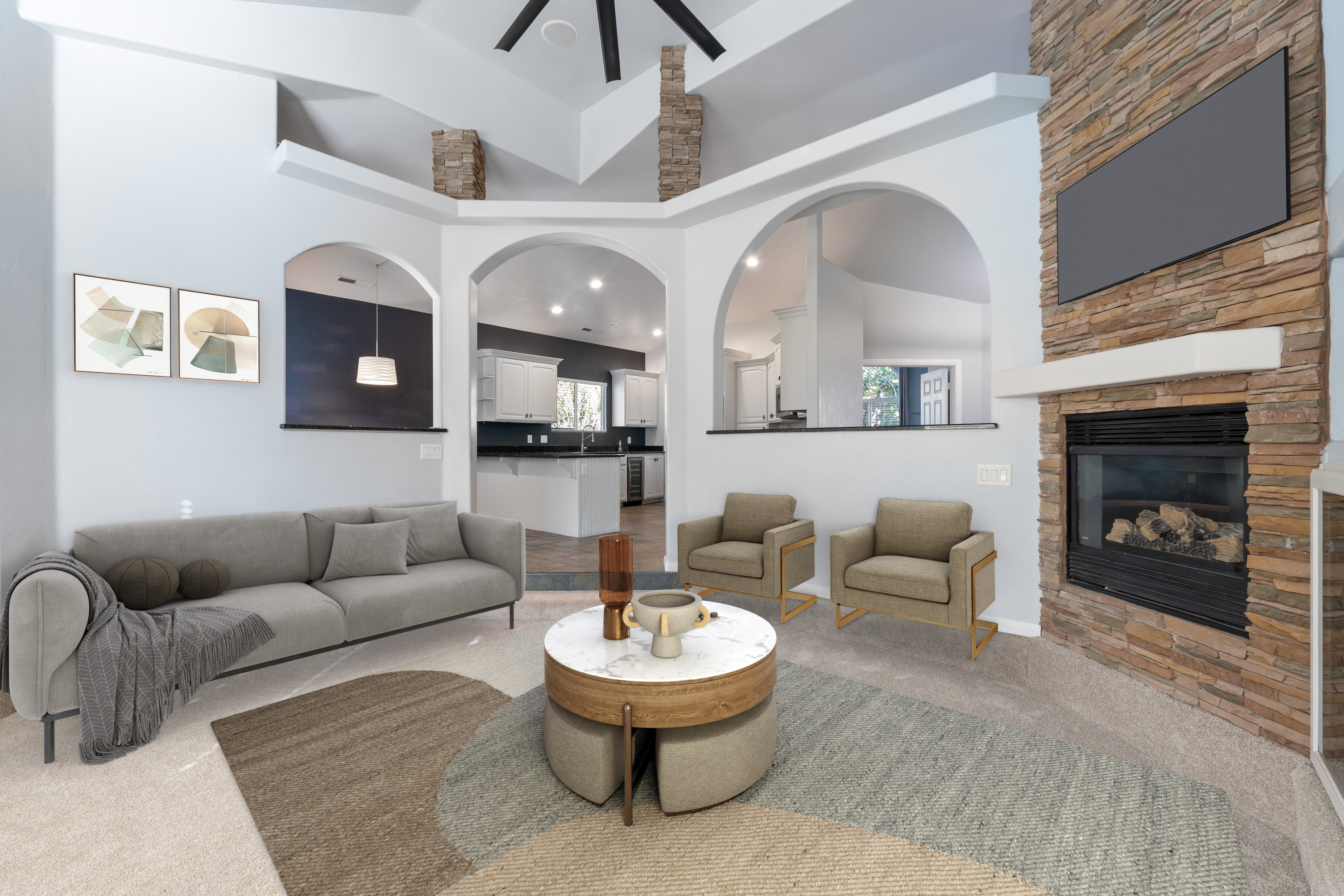 Living area with carpet, a high ceiling, a stone fireplace, and a ceiling fan