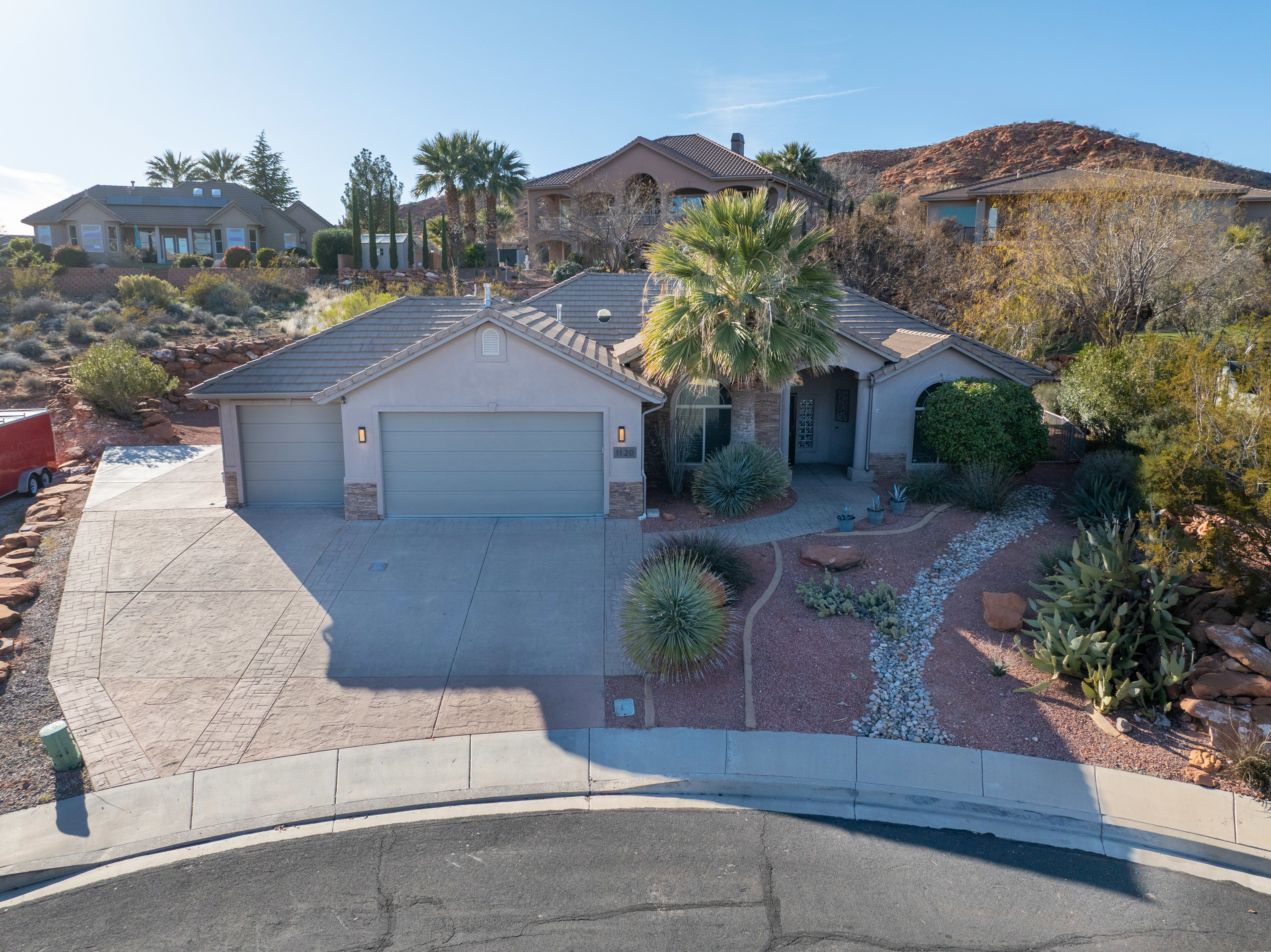 View of front of house featuring concrete driveway, stone siding, a garage, stucco siding, and a tiled roof