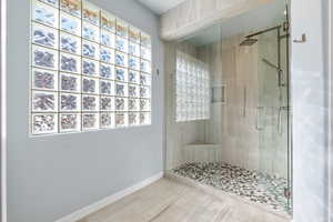 Bathroom featuring baseboards and a stall shower