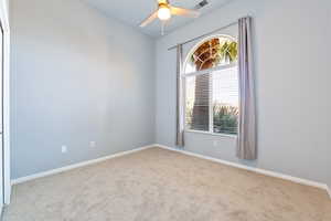 Carpeted spare room with baseboards and a ceiling fan