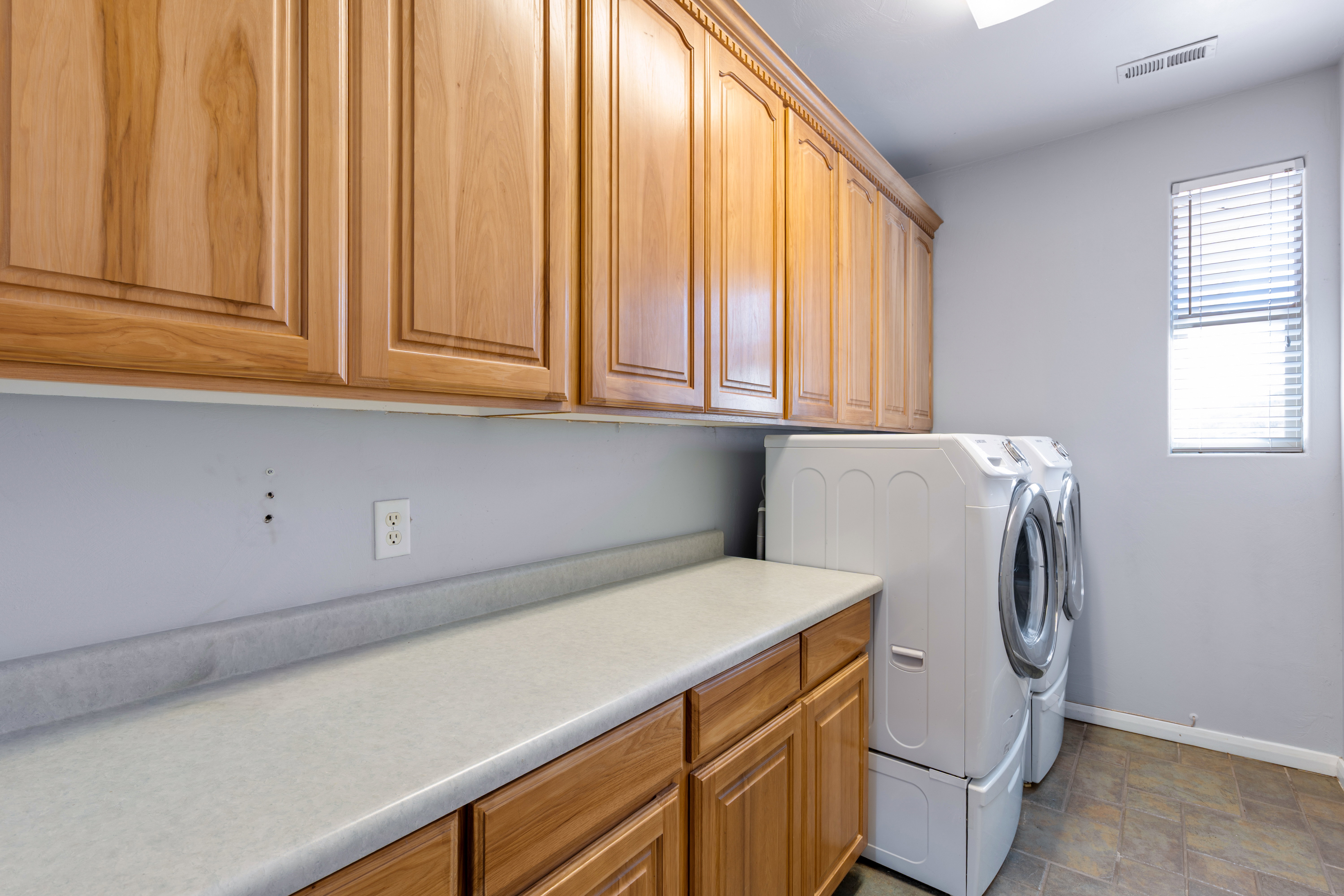 Washroom featuring independent washer and dryer, stone finish floors, and cabinet space