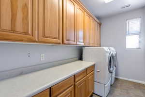 Washroom featuring independent washer and dryer, stone finish floors, and cabinet space