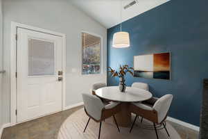 Dining area featuring stone finish flooring and vaulted ceiling