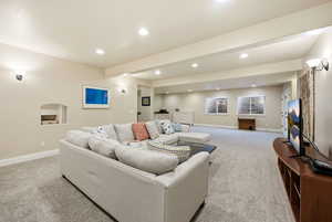 Living room with light carpet, beam ceiling, and recessed lighting