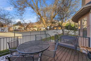 Wooden terrace featuring outdoor dining area, a fenced backyard, and a residential view