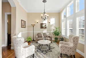 Living room with crown molding, wood finished floors, a chandelier, and arched walkways