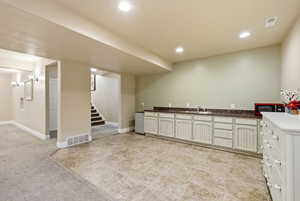 Bar area with light carpet, recessed lighting, and stairs