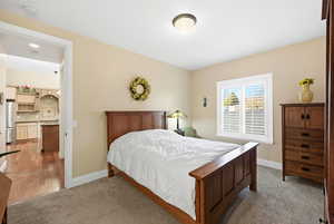 Bedroom featuring light colored carpet and freestanding refrigerator