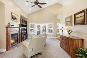 Living room featuring a tile fireplace, french doors, light colored carpet, arched walkways, and a ceiling fan
