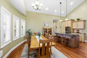 Dining area with light wood-style flooring, a chandelier, and high vaulted ceiling