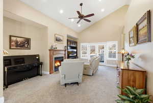 Living room featuring a tiled fireplace, light carpet, high vaulted ceiling, ceiling fan, and recessed lighting