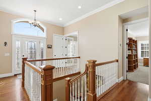 Entrance foyer with ornamental molding, wood finished floors, a chandelier, and recessed lighting
