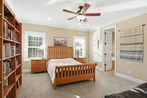 Bedroom with ensuite bath, light carpet, crown molding, a ceiling fan, and recessed lighting