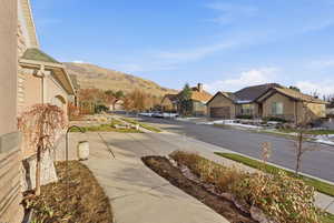 View of asphalt road with a residential view, sidewalks, a mountain view, and curbs