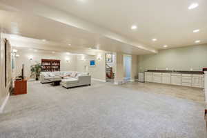 Living area with recessed lighting, light colored carpet, and stairway