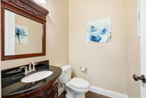 Half bath featuring vanity and dark tile patterned floors