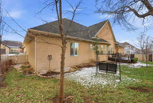 Back of house featuring stucco siding, a wooden deck, a shingled roof, and a gate