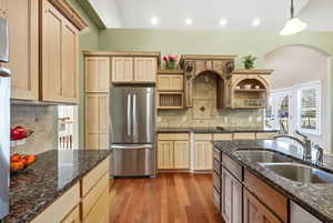 Kitchen featuring freestanding refrigerator, dark stone counters, light wood-style flooring, light brown cabinetry, and recessed lighting
