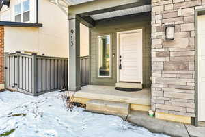 Property entrance featuring stone siding, a porch, and stucco siding