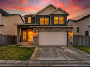 Craftsman house with board and batten siding, stone siding, driveway, an attached garage, and covered porch