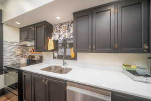 Kitchen with appliances with stainless steel finishes, under cabinet range hood, and light stone counters