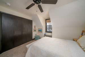 Carpeted bedroom featuring lofted ceiling, a closet, and ceiling fan