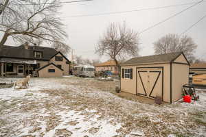 Snow covered structure featuring a storage unit