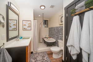 Bathroom featuring vanity, a shower with curtain, a soaking tub, and light wood-type flooring