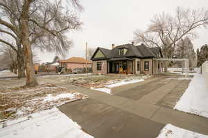 View of front of house with a chimney, covered porch, an attached carport, and concrete driveway
