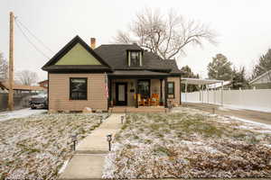 View of front of house with covered porch, a chimney, and a shingled roof