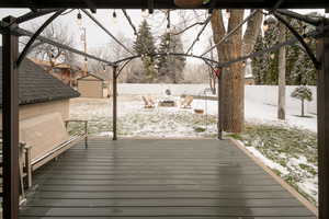 Snow covered deck featuring a storage unit and a fenced backyard