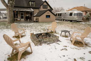 Snow covered patio with an outdoor fire pit, a patio area, and an outdoor structure