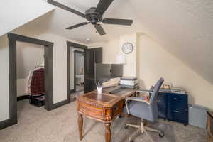 Home office with light colored carpet, lofted ceiling, a textured ceiling, and ceiling fan