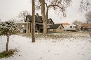 Snow covered back of property with a patio area and a chimney