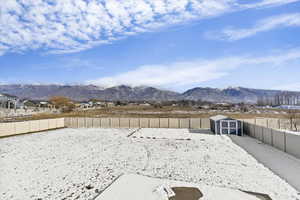 Fenced backyard featuring a mountain view and a shed