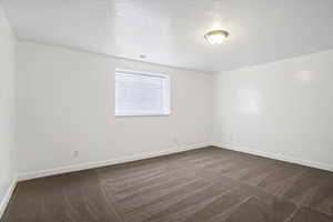 Spare room with dark colored carpet and a textured ceiling
